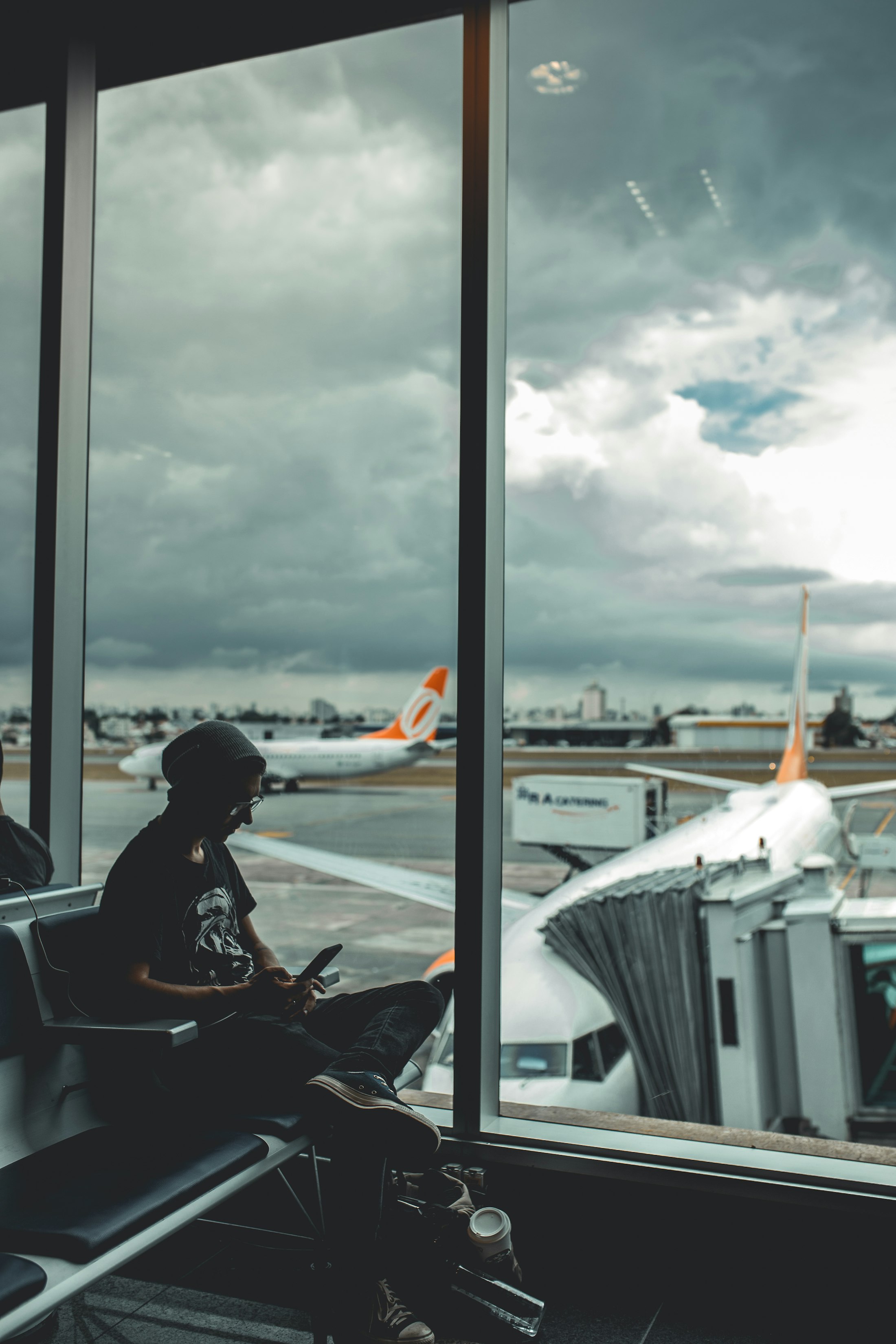 A creator on their phone at an airport gate, planes outside