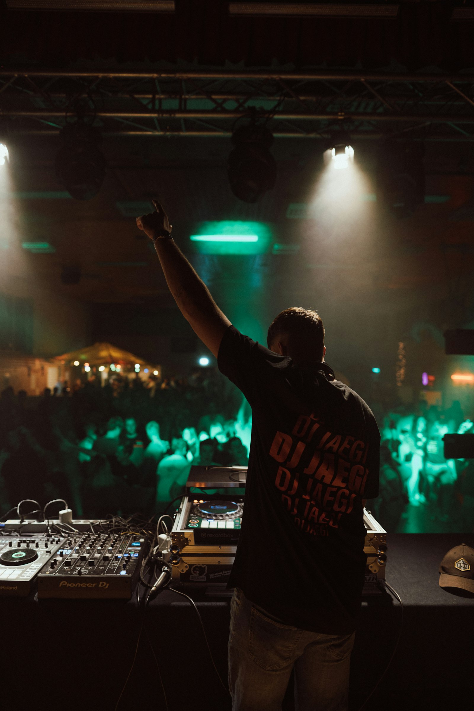 A DJ with an arm raised over a lit crowd