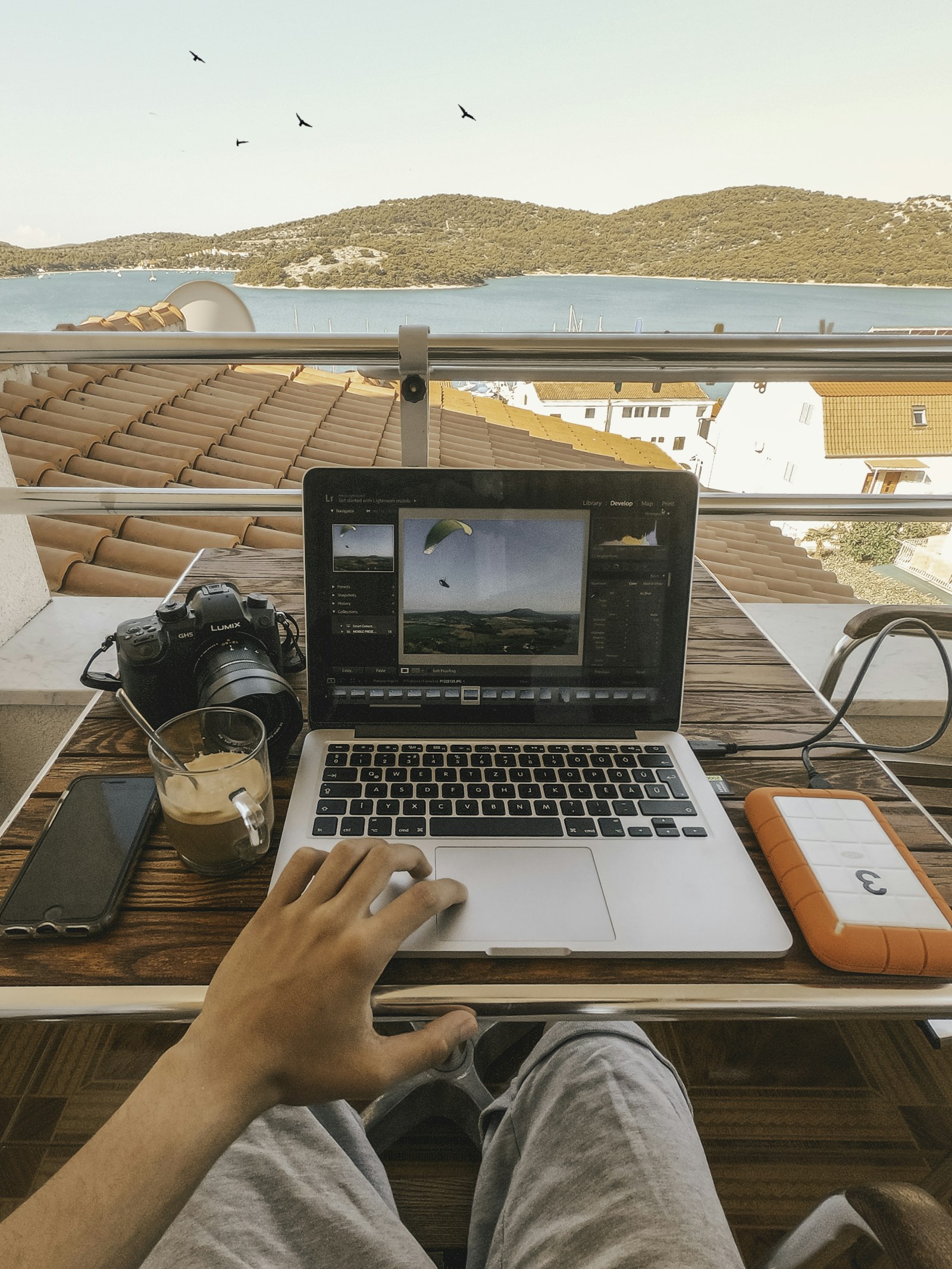 A creator editing video on a laptop on a balcony over a bay